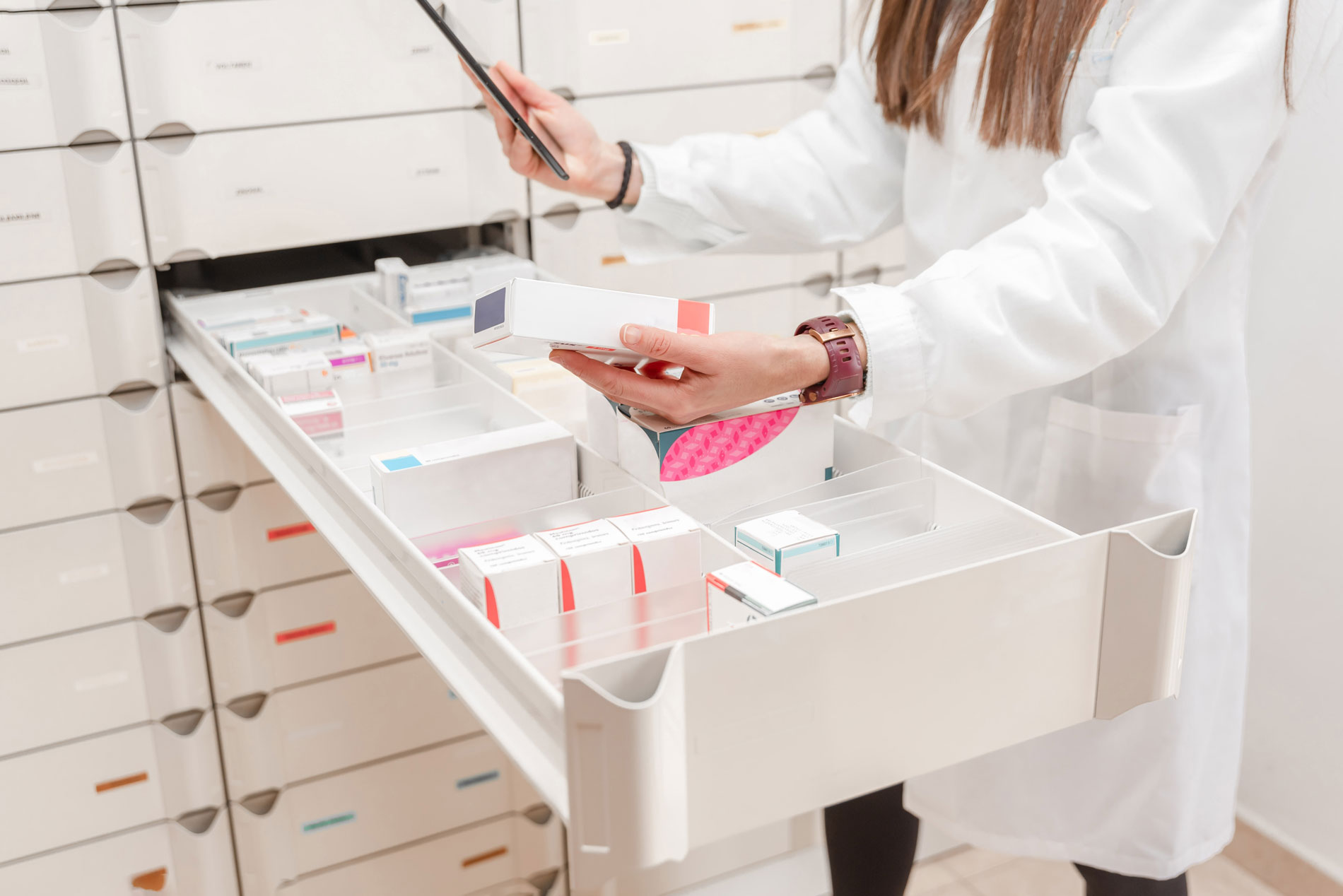 Farmaceutka organizująca leki na p&oacute;łkach aptecznych podczas skanowania produkt&oacute;w medycznych i suplement&oacute;w. 